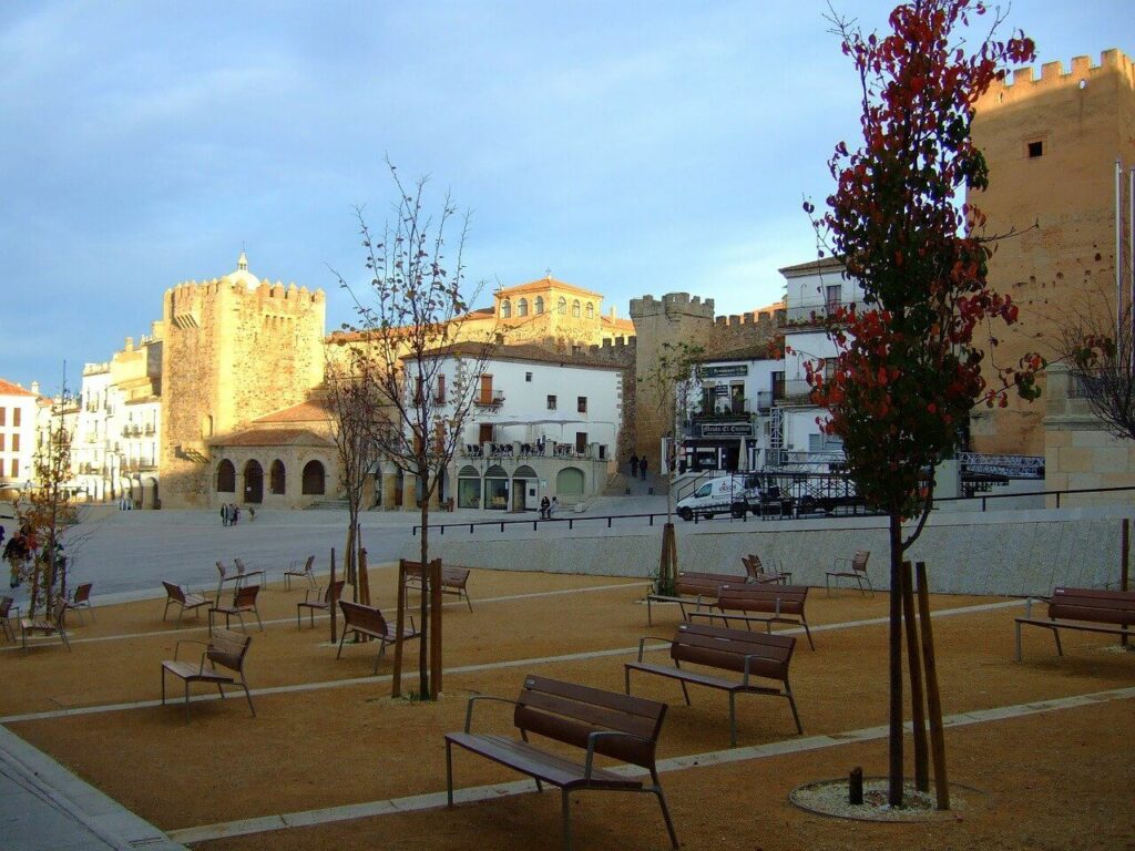 Vista de la plaza mayor con la Torre de Bujaco al fondo, uno de los lugares históricos para visitar en la ciudad.